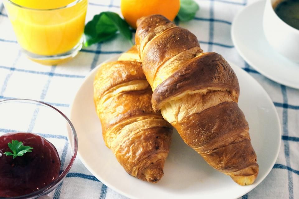 Deux croissants, un jus d'orange et une confiture sur une nappe à carreaux